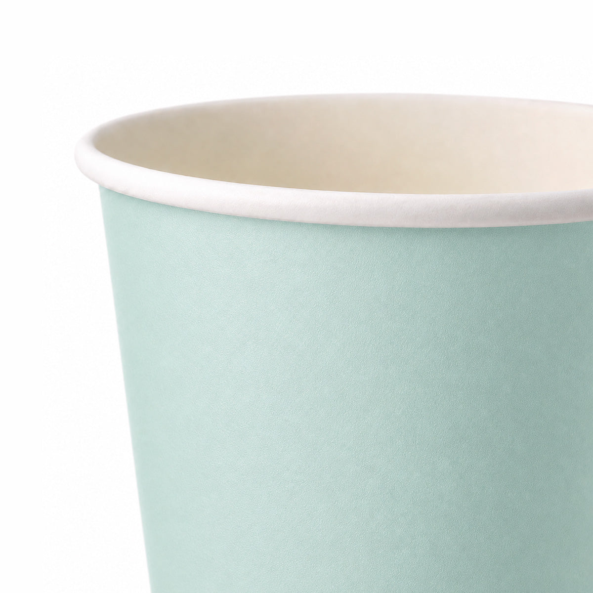 A close-up of a paper cup with a light mint green exterior and a cream-colored interior, shown against a plain white background.