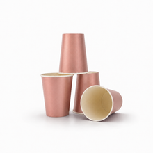 Four metallic rose gold paper cups of different orientations on a clean white background.