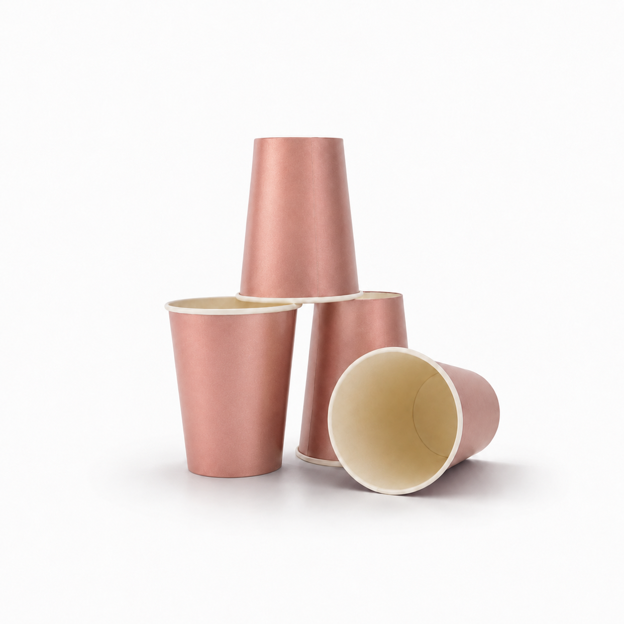 Four metallic rose gold paper cups of different orientations on a clean white background.