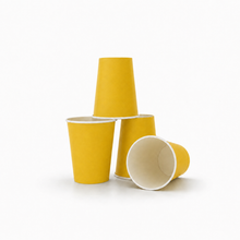 Three yellow paper cups arranged on a white background, with one standing upright, one lying on its side showing the white interior, and one standing behind the others.